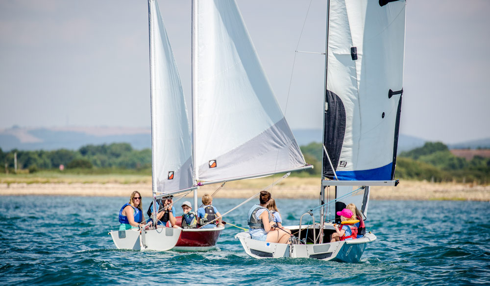 family sailing two boats on day out on the water