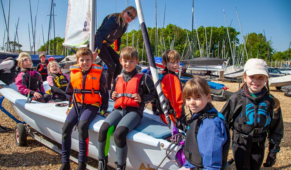 kids sat on sailing boat in the boat yard at their club