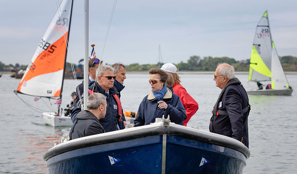 Princess Anne in a sailing dinghy, talking to other people on the water - 2E8X1RY